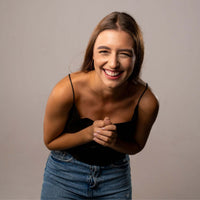 Thumbnail for Cheerful woman smiling and laughing while wearing a black top and denim shorts.