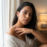 Thumbnail for Pave Cross Huggie Hoops in Silver, worn by a window | SKU: 41006-silver