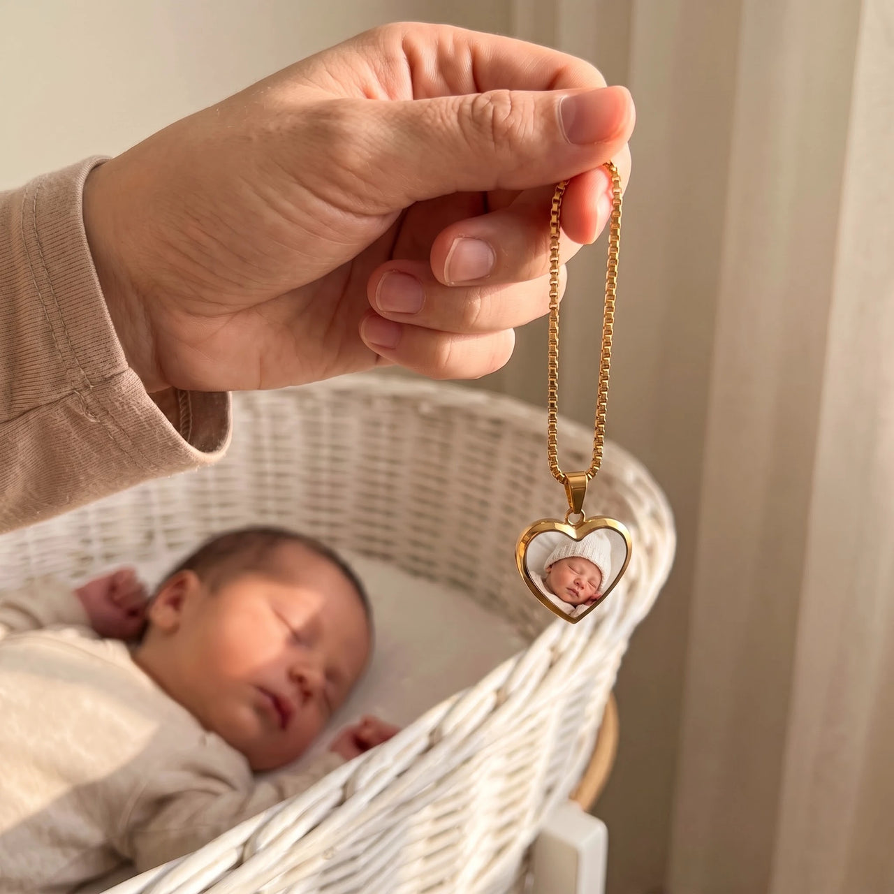 The gold heart photo pendant held above a sleeping newborn, showing its real small size | SKU: TPH-CHTN-GOLD-SMALL