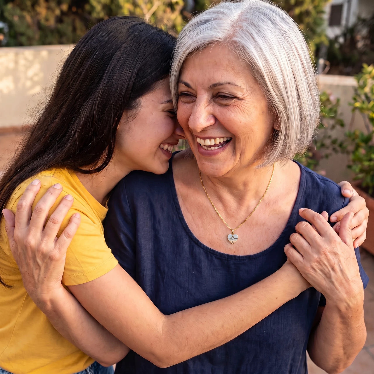 Grandmother hugging her granddaughter, wearing the gold secret heart photo necklace | SKU: TPH-CHTN-GOLD-SMALL